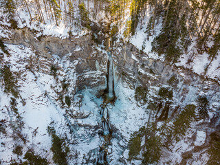 Obraz premium Spectacular drop down view of waterfall falling over rocky forest ledge.