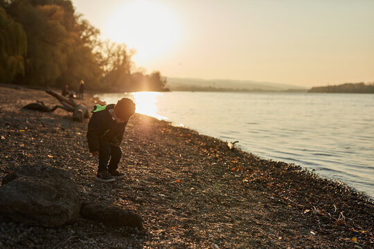 Child Playing With Pebble By The River