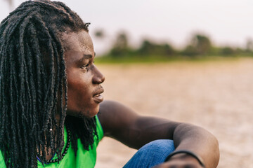 Serious black man sitting on beach
