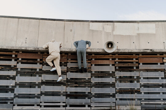 Friends climbing a wall helping each other