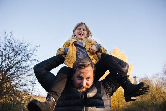 Dad lifting daughter for shoulder ride