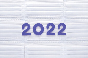 Violet felt new year numbers 2022 on white medical masks background. Inspired by trendy very peri color of the year 2022. Place for your text here. - obrazy, fototapety, plakaty