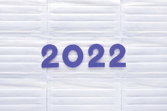 Violet felt new year numbers 2022 on white medical masks background. Inspired by trendy very peri color of the year 2022. Place for your text here.