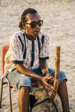 African musician playing kora on beach