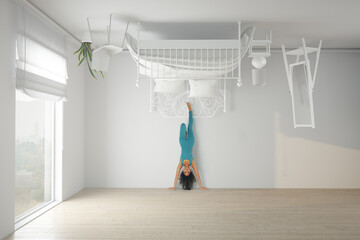 Woman doing a headstand in an upside down bedroom
