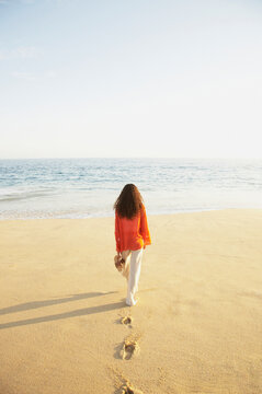 Woman on vacation walking on beach towards the ocean