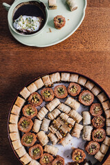 assorted circular tin of middle eastern baklava filo dough pastry sweets with green cup of hot chocolate	