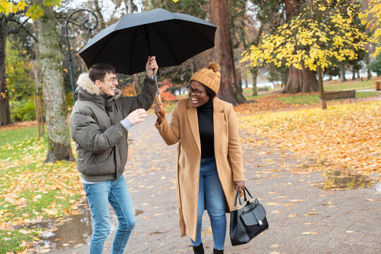 couple laughing outside holding umbrella, rainy weather
