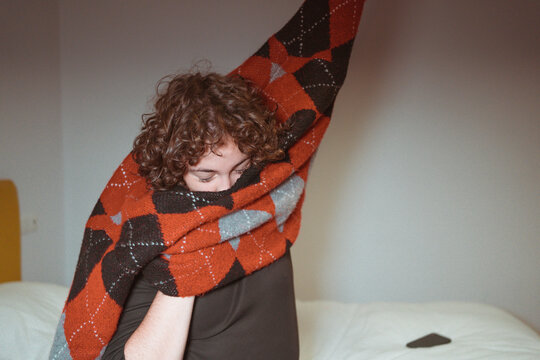 Teen girl taking off vintage sweater in bedroom 