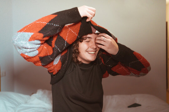 Funny girl taking off vintage sweater in bedroom 