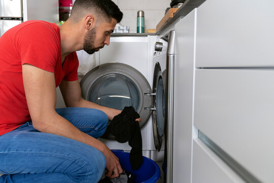 man taking wet clothes out of the washing machine