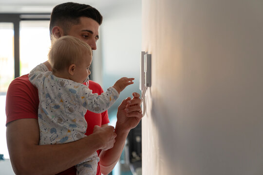father with baby going to the intercom on the wall