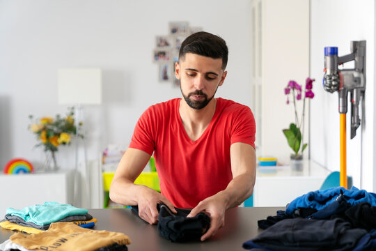 man folding clothes and placing them in piles