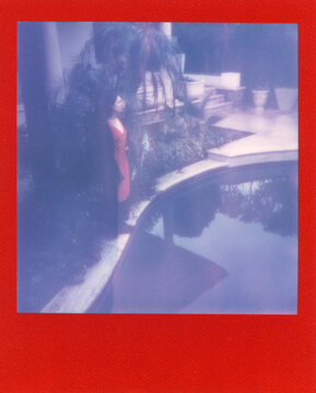 a dreamy woman in red near a abandoned swimming pool