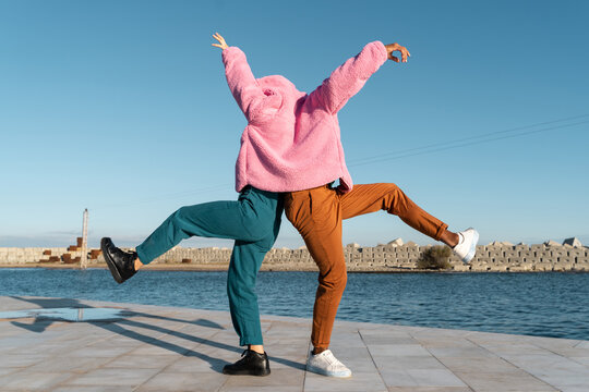 Friends sharing colorful jacket while dancing 