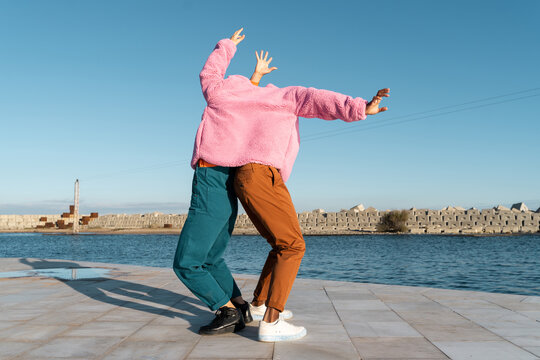 Friends sharing colorful jacket while dancing 