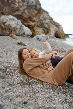 woman and kid walking on the shore of the cold sea