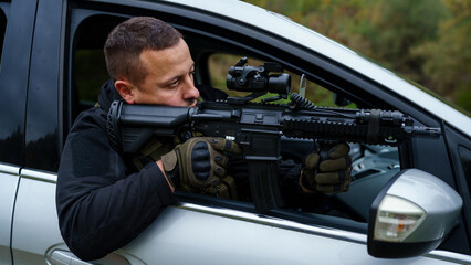 One man special force police or terrorist holding automatic weapon shooting and aiming from the car...