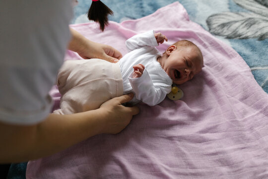 Crying baby laying on the bed at home