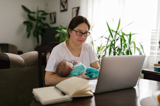 Mother working from home and holding baby
