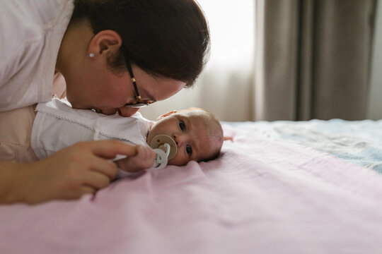 Mother Kissing Baby's Stomach In The Bedroom