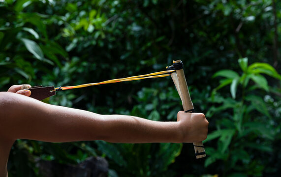 Young boy pulls back on slingshot to shoot