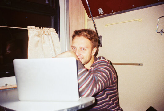 Cheerful man with laptop in train