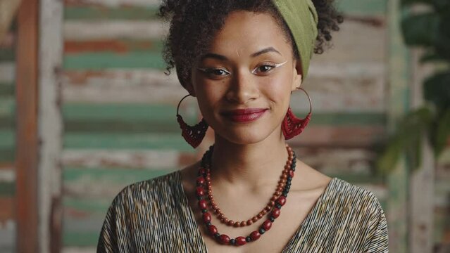 Close up portrait of young fashionable african american lady wearing ethno clothes and accessories smiling to camera
