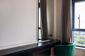 Bureau table in bedroom with green chair next to window