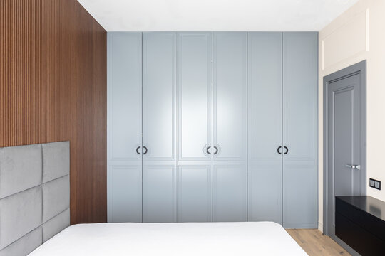 Grey wardrobe with closed doors in a minimalist bedroom