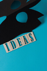 black paper mask and the word "ideas" on a blue background
