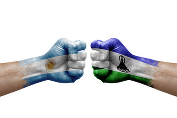 Two hands punch to each others on white background. Country flags painted fists, conflict crisis concept between argentina and lesotho