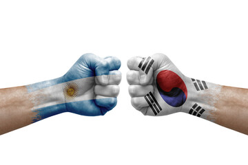 Two hands punch to each others on white background. Country flags painted fists, conflict crisis concept between argentina and south korea