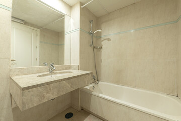 white earthenware sink set in light marble veined countertop, inlaid wall mirror and white bathtub