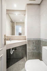 Bathroom with corner marble top and half green tiles with border and light tiles in the other half