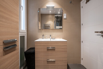 Bathroom with light woodgrain furniture, white porcelain sink, square frameless mirror and white door