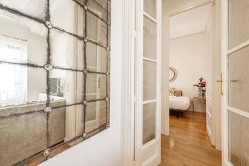Apartment with white painted wooden doors and oak floors, vintage mirrors, glass windows and white painted radiators