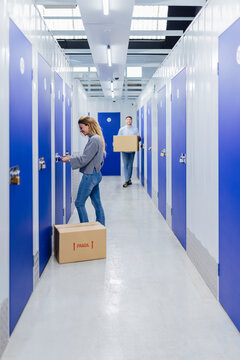 Young woman opening padlocks on a blue door of a storage roo