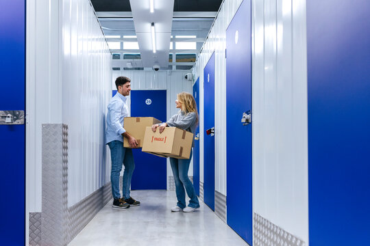 Young couple with carton boxes in storage room corridor