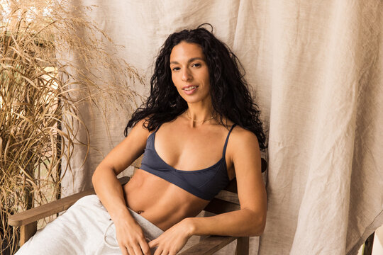 Woman in cozy sweatpants and sport bra smiling