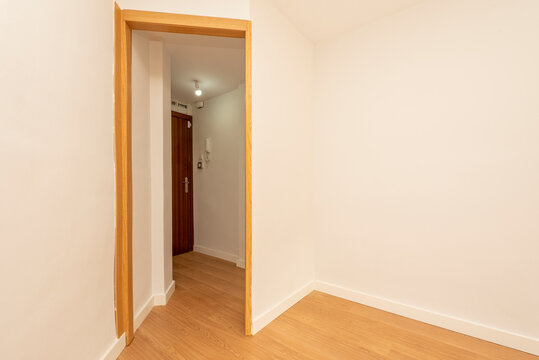 empty room with oak door and light colored wooden floor with entrance hall