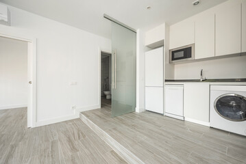 Living room and kitchen of apartment on two levels with white kitchen furniture and ceramic...