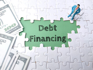 Top view banknotes and miniature people with text Debt Financing on a white puzzle background