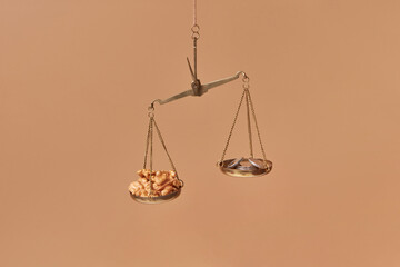 Golden scales with pile of coins and walnuts