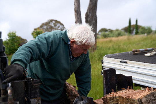 Senior man splitting large logs