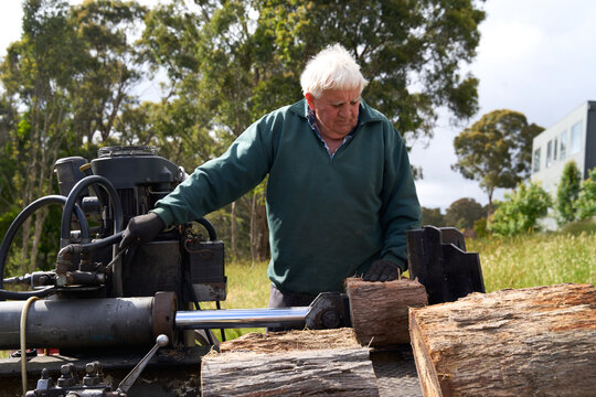 Logs being split by senior on rural property