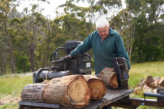 Senior man splitting logs for firewood