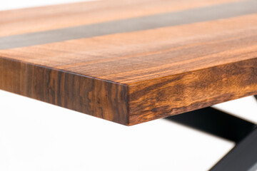 Close up of a Curly Bastogne Walnut wooden coffee table with black epoxy resin and metal legs. White studio backdrop.