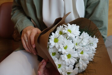 Young girl holding a bouquet of white daisies wearing hijab