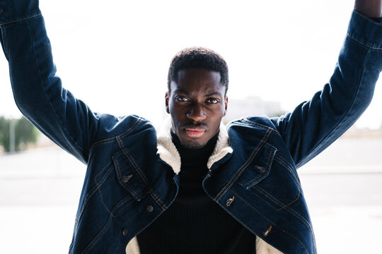 Black male raising arms on street